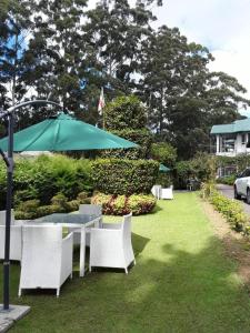 a table and chairs with an umbrella on the grass at The Trevene Hotel in Nuwara Eliya