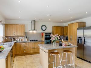 uma cozinha com armários de madeira e um frigorífico de aço inoxidável em Cunliffe Cottage em Hathersage