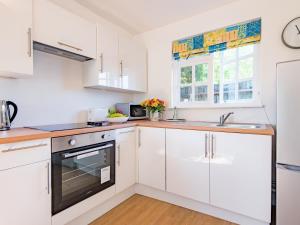 a kitchen with white cabinets and a sink at Mitford Lodge in Wye