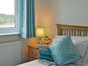 a bed with a blue pillow and a lamp on a night stand at Mariners Rest in Bideford