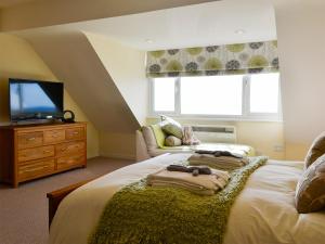 a bedroom with a bed with a television and a couch at Morlais - Hw7599 in Llanaber