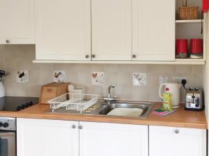 a kitchen sink with a dish drying rack on the counter at The Wee House in Muthill