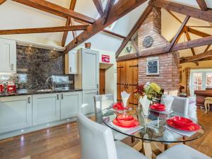 cocina y comedor con mesa de cristal y sillas en Cowslip Cottage, en Swarland