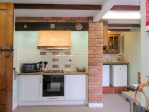 una cocina con armarios blancos y una pared de ladrillo en Mallard Cottage en Grosmont