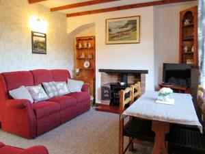 sala de estar con sofá rojo y chimenea en Mallard Cottage en Grosmont