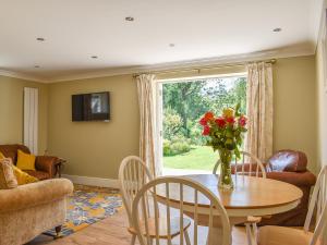 a living room with a table with a vase of flowers on it at Duck Cottage in Winterbourne Dauntsey