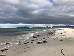 una playa de arena con el océano y un cielo nublado en Taigh Violet Rose, en Gramisdale