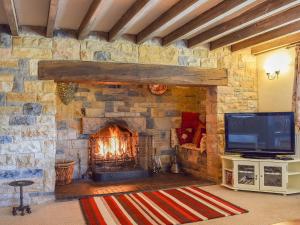 a living room with a stone fireplace with a tv at Broadmeadows Farm in Butterton