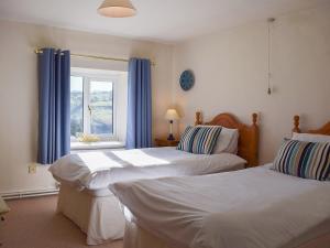 a bedroom with two beds and a window with blue curtains at Broadmeadows Farm in Butterton
