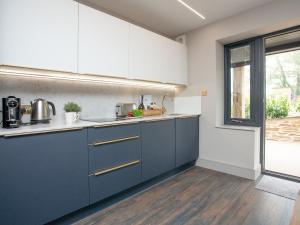 una cocina con armarios azules y una ventana en The Oyster en Turnchapel