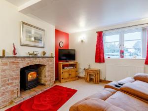 a living room with a fireplace and a tv at The Old Vicarage in Stowe