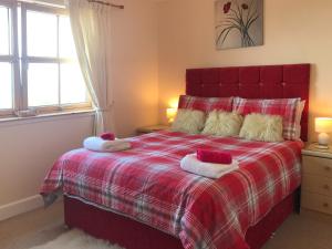 Un dormitorio con una cama roja con toallas. en Beith, en Kilmuir