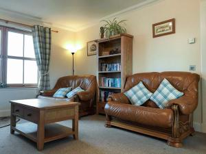 uma sala de estar com dois sofás de couro e uma estante de livros em Beith em Kilmuir