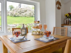 una mesa de madera con dos platos de comida y copas de vino en Manor Park Cottage, en Knitsley