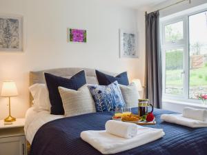 Un dormitorio con una cama azul con una bandeja de comida. en Manor Park Cottage en Knitsley