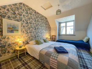 a bedroom with a bed and a wall with floral wallpaper at Fishermans Cottage in Gardenstown