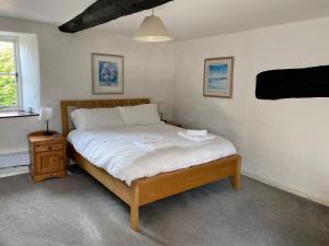 een slaapkamer met een groot bed met witte lakens en een raam bij Flood House in Bridport