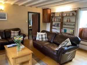 een woonkamer met een leren bank en een salontafel bij Flood House in Bridport