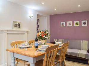 a dining room with a table and chairs and a couch at Pinch Cottage in Neyland