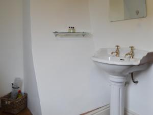 a white bathroom with a sink and a mirror at Bakers Cottage in Hotham