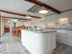 a kitchen with white cabinets and a large island at Orchard Barn in South Tawton