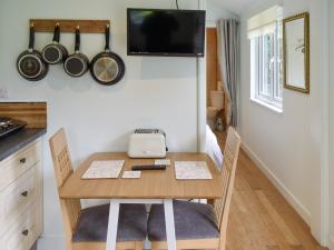 uma pequena mesa com duas cadeiras e uma televisão na parede em Shepherds Hut 3 At Laddingford - Uk32532 em Yalding