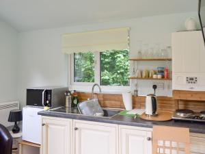 uma cozinha com armários brancos, um lavatório e uma janela em Shepherds Hut 3 At Laddingford - Uk32532 em Yalding