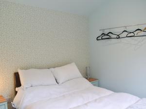 a bedroom with a white bed and a wall at Shepherds Hut 3 At Laddingford - Uk32532 in Yalding