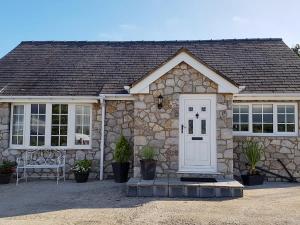 a stone house with a white door and windows at The Paddock in Bodelwyddan