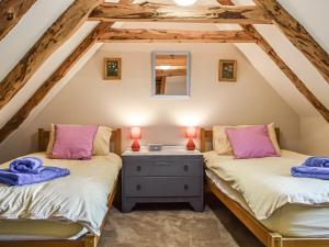 2 łóżka pojedyncze w sypialni na poddaszu z drewnianymi belkami stropowymi w obiekcie The Thatched Cottage w mieście St Andrews