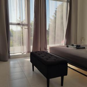 ein Schlafzimmer mit einem Bett und einem Hocker vor einem Fenster in der Unterkunft STUDIOS POSEIDONIA apartments 50 & 70 sqm with sea view in Korinthos