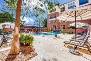 a swimming pool with two benches and an umbrella at Cozysuites Lovely 1BR Prairie Crossing Apartment 3 in Farmers Branch