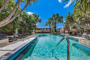 a swimming pool with chairs and palm trees at Mirage Whitsundays in Airlie Beach