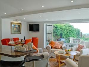 a living room with orange and white furniture and a large window at The Cottage in Cheltenham