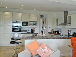 uma cozinha com armários brancos e uma ilha com um sofá em The Cottage em Cheltenham