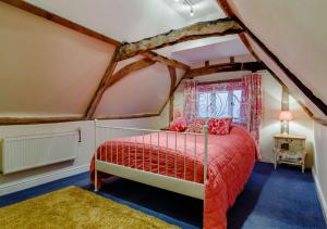 um quarto com uma cama vermelha num sótão em Street Farm-Metfield em Metfield