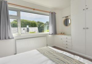 a white bedroom with a window and a bed at Llys Neigwl in Abersoch