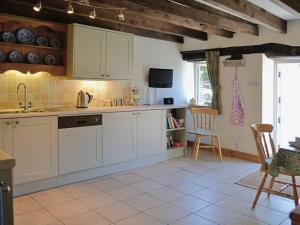 cocina con armarios blancos, mesa y sillas en Shamrock Cottage en Cenarth