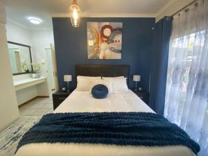 1 dormitorio con 1 cama grande y pared azul en CozyatCaley - Private Apartment, en Centurion