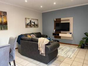 a living room with a couch and a flat screen tv at CozyatCaley - Private Apartment in Centurion