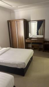 1 dormitorio con 2 camas, escritorio y espejo en ريف الشاطئ للشقق الفندقية, en Dammam