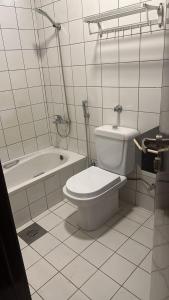 a white bathroom with a toilet and a bath tub at ريف الشاطئ للشقق الفندقية in Dammam