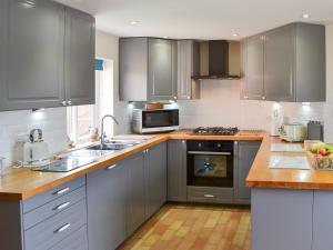 a kitchen with stainless steel appliances and gray cabinets at Stepping Stone Cottage in Bacton