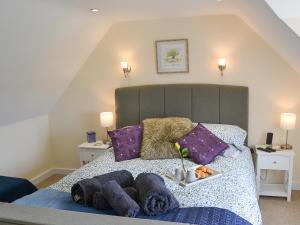 a bedroom with a large bed with purple pillows at Stepping Stone Cottage in Bacton