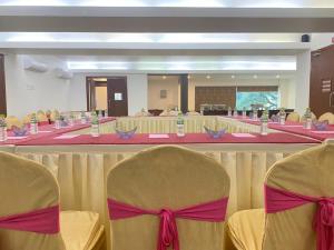 een vergaderzaal met stoelen en een tafel met roze bogen bij Kings Hotel Egmore in Chennai