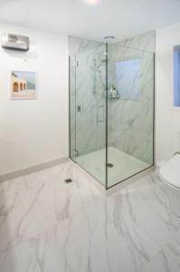 La salle de bains est pourvue d'une douche en verre et de toilettes. dans l'établissement Beach Front Abode- 2 Bed 2 Bath, à Christchurch