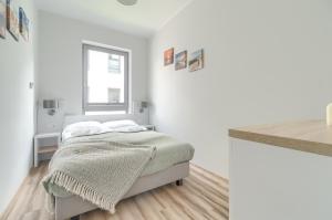 a white bedroom with a bed and a window at Apartament Doris 2 - 50 m do plaży in Pobierowo