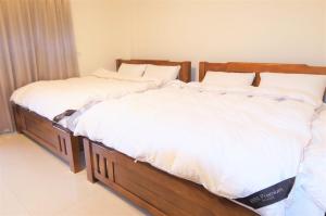 two twin beds in a bedroom with white sheets at Yellow Bell in Guiren
