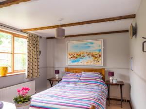 a bedroom with a bed with a colorful striped comforter at The Barn in Coltishall