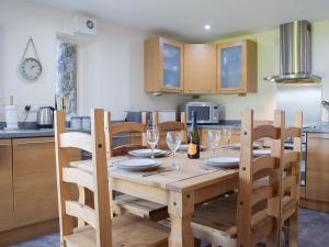 a kitchen with a wooden table and chairs with wine glasses at Barn Cottage in Talley